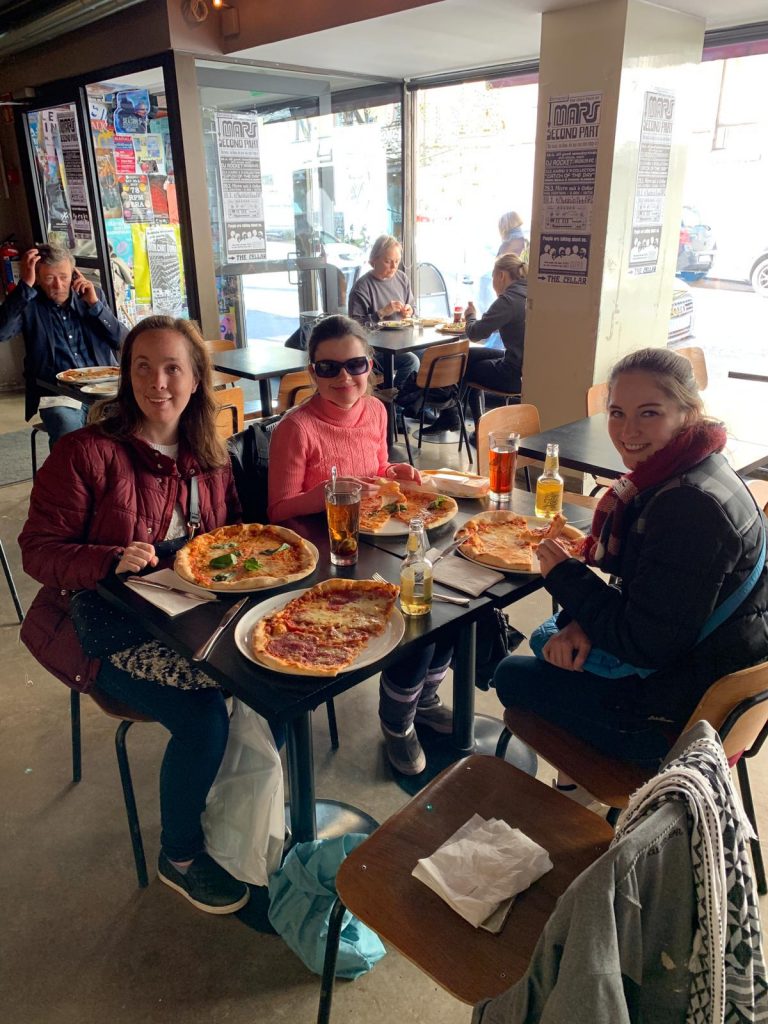 Laurel and her traveling companion Sarah eat pizza with Anastasiya in Helsinki.