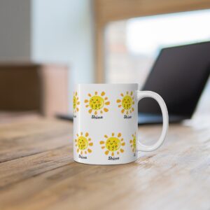 white ceramic mug with a sunshine design that has LWF in print and Braille and the word Shine on a repeating pattern